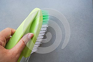 Hand with green washing brush on the textile floor for cleaning