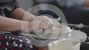 Close-up of the hand of a grumpy woman master works on a potter's wheel in slow motion. Making utensils with your own