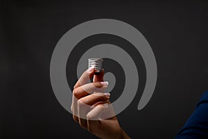 Close up of hand holding bulb screw base against black background