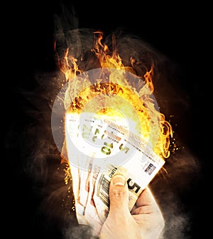 Close-up of hand holding burning bank notes waste of money concept