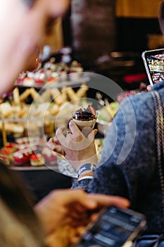 Close-up of hand holding a chocolate dessert with berries on top at an event