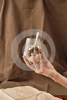 Close up of hand holding delicious layered dessert in glass jar, Homemade yogurt with granola and berries, Granola baked