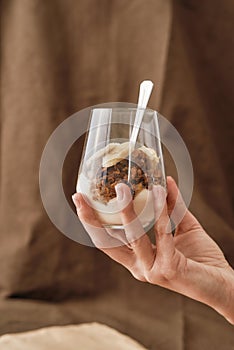 Close up of hand holding delicious layered dessert in glass jar, Homemade yogurt with granola and berries, Granola baked