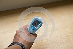 Close up of a hand holding a digital infrared thermometer thermometer gun  on white