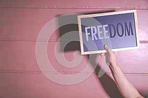 Close up Hand holding Freedom text on dark background