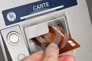 Close up of a hand holding a french credit card in ATM cash dispenser