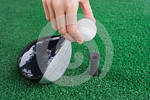 Close-up Hand holding golf ball and a golf wood on a driving ran