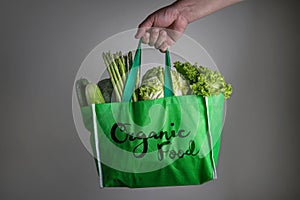 Close up a hand holding green grocery bag with Organic Food text