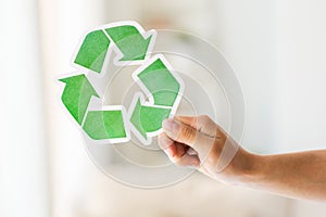 Close up of hand holding green recycle symbol