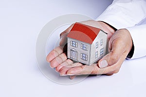 Hand holding house paper for Mortgage loans concept