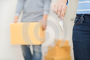 Close up of hand holding a key while a man holding a box to move
