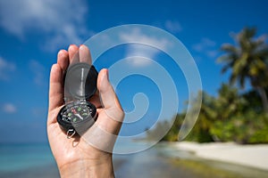 Close up of the hand holding a magnetic compass over a landscape