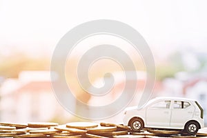 Close up hand holding model of toy car white on over a lot money of stacked