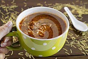 A hand holding a mug with traditional Turkish vermicelli soup