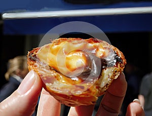 Close up a hand holding a Pasteis de nata traditional Portugese pastry cuisine egg tart with creamy filling, custard