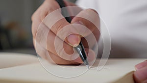 Close up of hand holding pen and writing on empty book paper