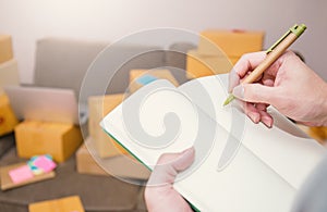 Close up hand holding pen writing note on a book.