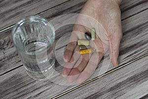 Close-up of a hand holding pills and a glass of water. Nutritional supplements. Sport, diet concept. Capsules, healthy lifestyle