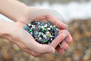 Close Up Of Hand Holding Plastic Granules Polluting Beach photo