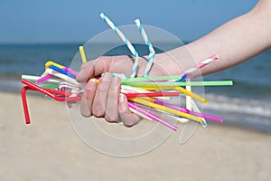 Close Up Of Hand Holding Plastic Straws Polluting Beach photo