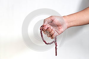 close up of hand holding prayer beads isolated on a white background