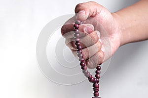 close up of hand holding prayer beads isolated on a white background