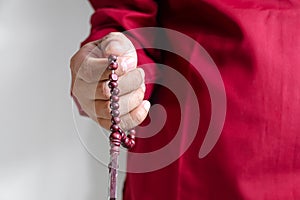 close up of hand holding prayer beads  on a white background