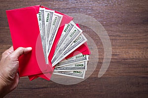 Close-up of hand holding a red envelope packet with money dollars or Ang Pao prepare for given to children during Chinese New