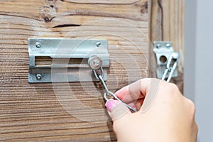 Close up of hand holding security door chain on wooden door