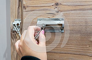 Close up of hand holding security door chain on wooden door