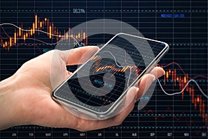 Close up of hand holding smartphone with falling red crisis forex chart on dark grid background. Recession, trade and downfall