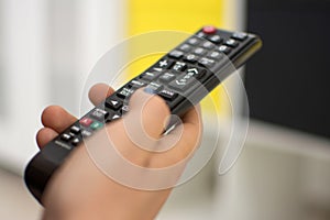 Close up of a hand holding a television remote control. Selective focus