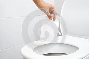 close up hand holding a tissue to be thrown into the toilet bowl. Can not drain water