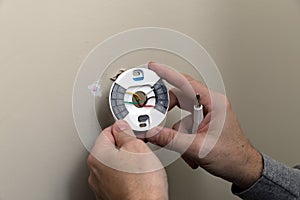 Close-up of Hand installing mounting plate for modern round thermostat for air conditioning unit