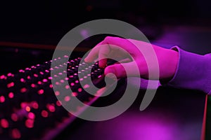 Close-up of a hand on a keyboard in neon color. Selective focus