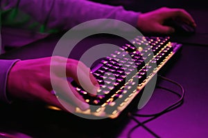 Close-up of a hand on a keyboard in neon color. Selective focus