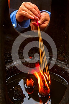 A Close-up on hand lighting the incense
