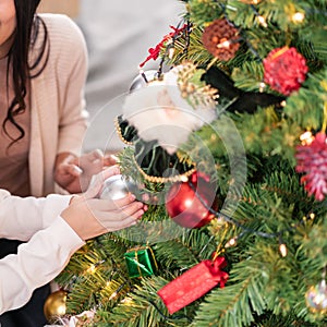 Little girl decorate christmas tree with ornament