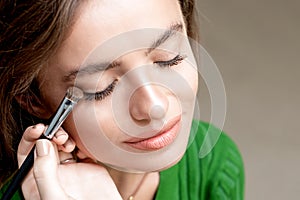Close up hand of makeup artist applying eyeshadow powder