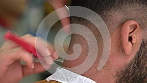 Close up hand of male barber shaving nape of customer with straight razor.