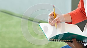 Close up hand of male teenager writing with pencil on notebook a