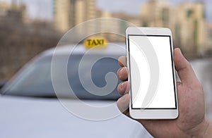 Close-up of a hand of a man holding a mobile phone in the background of a car and a city