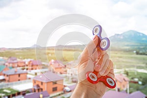 Close-up of a hand of a man holding a two spinners machine on the background of a cityscape fidgeting hand toy