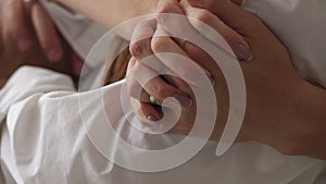 Close-up of the hand of a man hugging his girlfriend by the shoulders on the bed