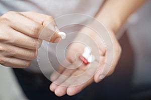 Close up hand man taking multiple colors pills