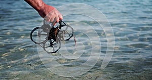 A close-up of the hand of a man who takes the FPV drone out of the water
