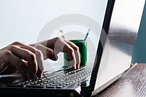 Close-up of the hand of a man, writer or blogger who is typing text on the laptop keyboard. Concept of blogging, computer work in