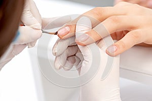Hand of manicurist applying clear nail polish