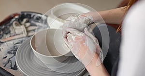 Close-up of the hand of a master potter working on a potter's wheel, forming a bowl of clay. Slow motion