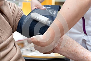 Close up hand of nurse working and adjusting blood pressure gauge on senior woman hand in nursing home